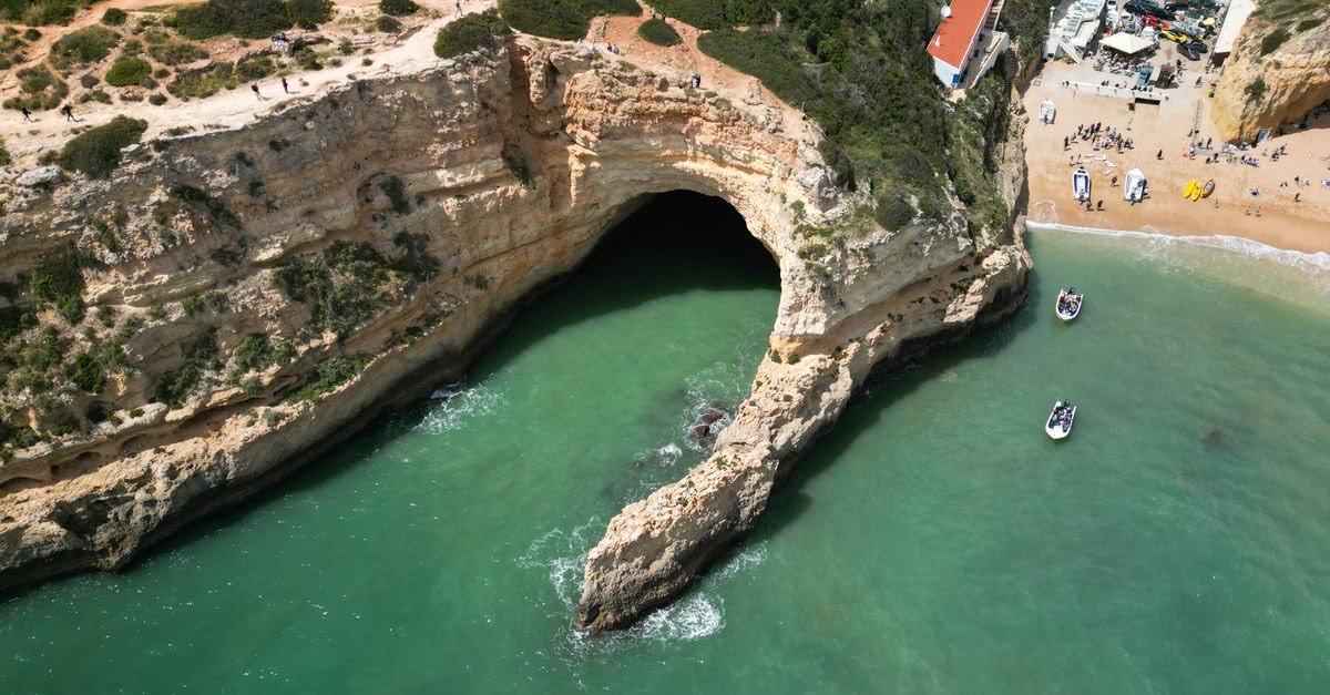 The Benagil sea cave from above, with its round ceiling opening and strip of sand