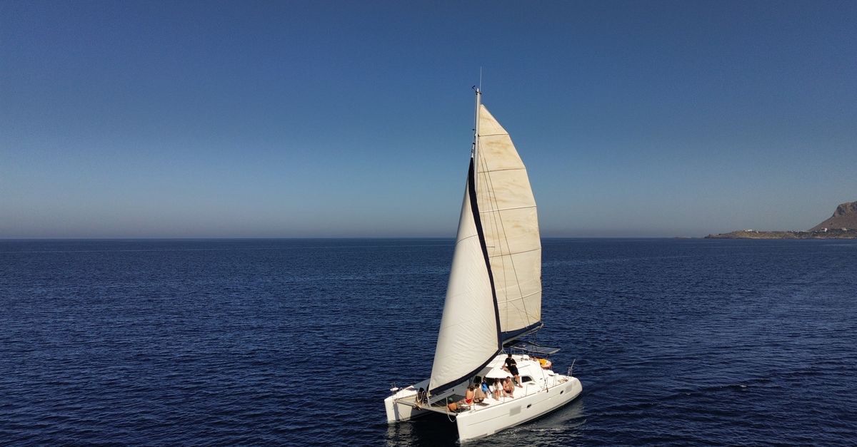 A catamaran on the open sea off the Algarve coast under a clear sky
