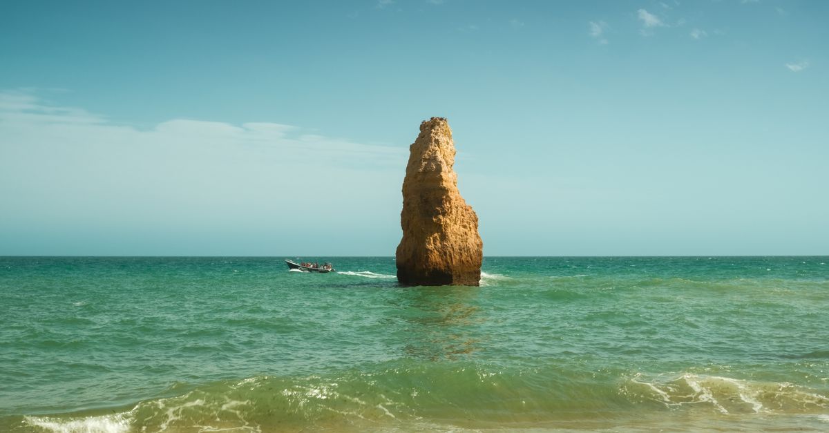 Child sitting on a boat bench under a sun canopy, looking out over the Algarve coast
